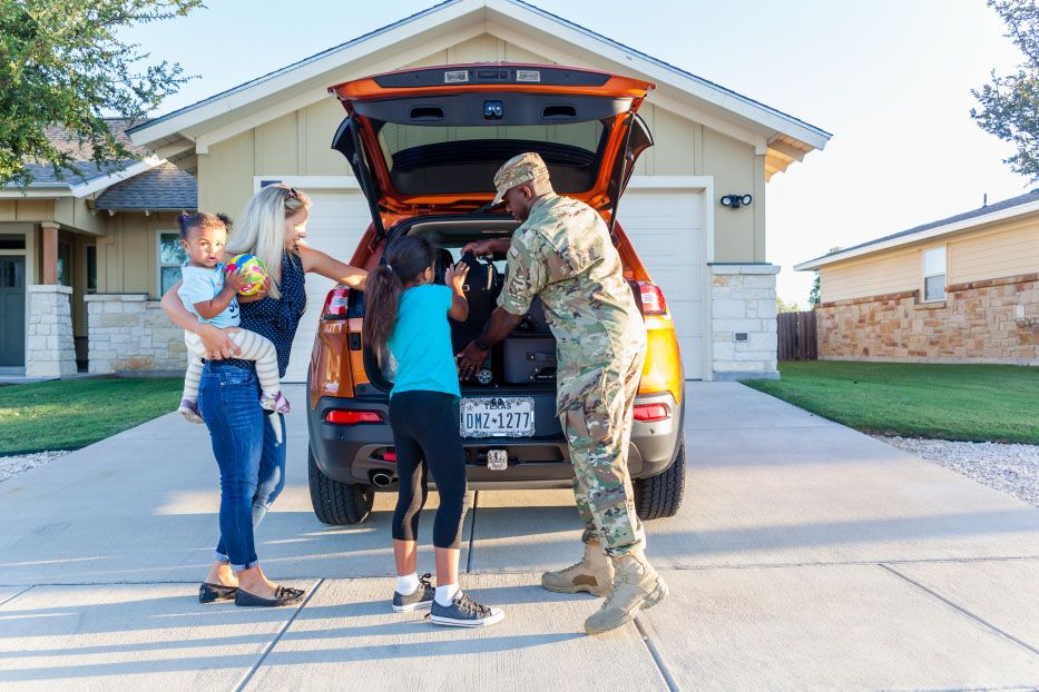 Service member and family unpacking a car
